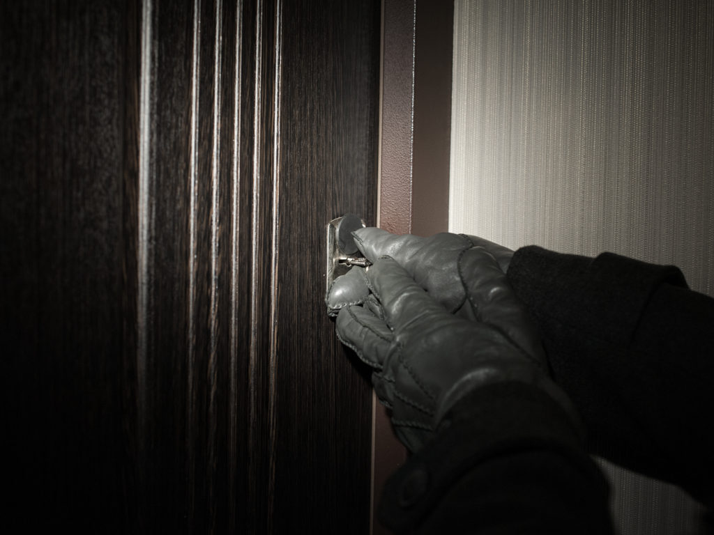 man's hand in a glove opening the door.